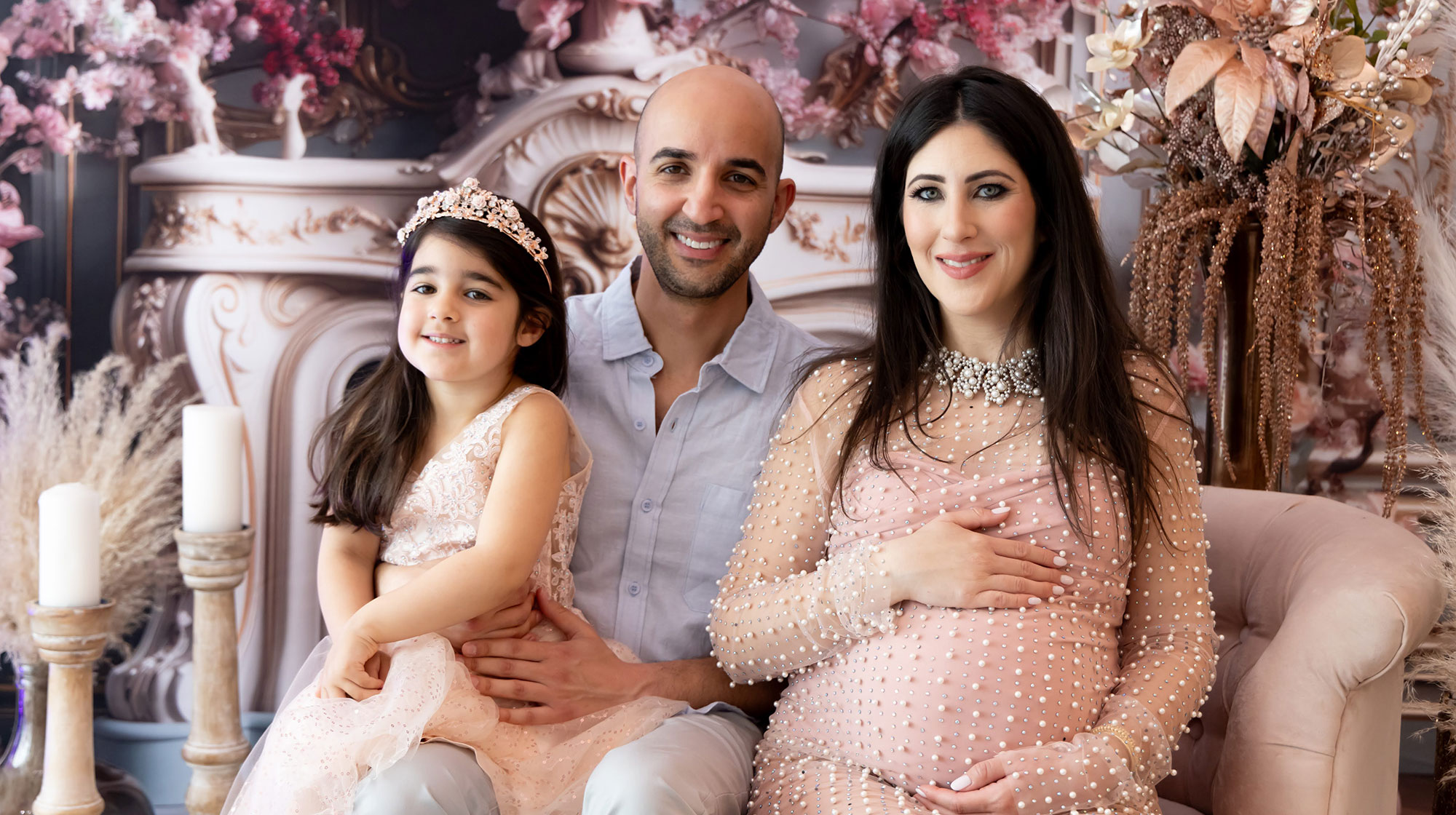 Professional photo of Jonathan beside his pregnant wife and daughter.